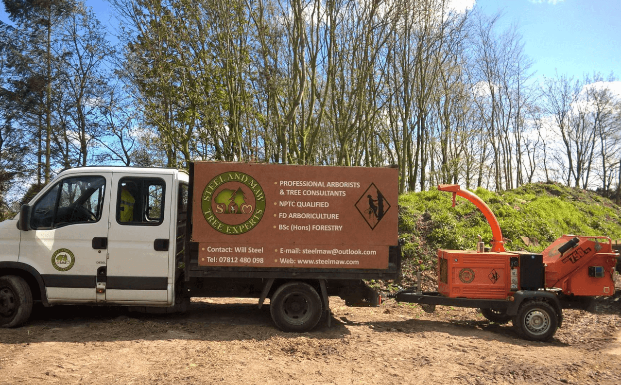 The Steel and Maw van in front of some young forest trees